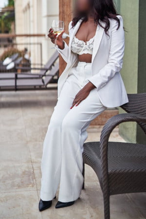 Classy black lady in a white suit holding a glass of bubbly