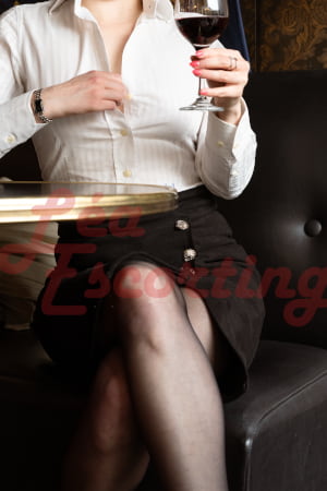 Elegant woman in a black pencil skirt and white short holding a glass of red wine