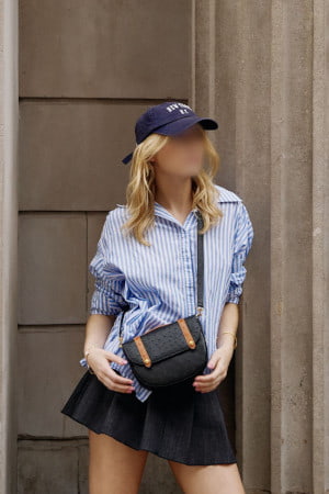 Tall young blonde in a striped shirt standing in front of large columns