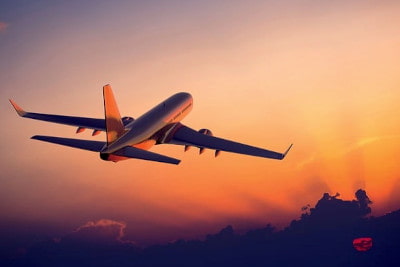 An airplane flying with an impressive orange sunset in the background